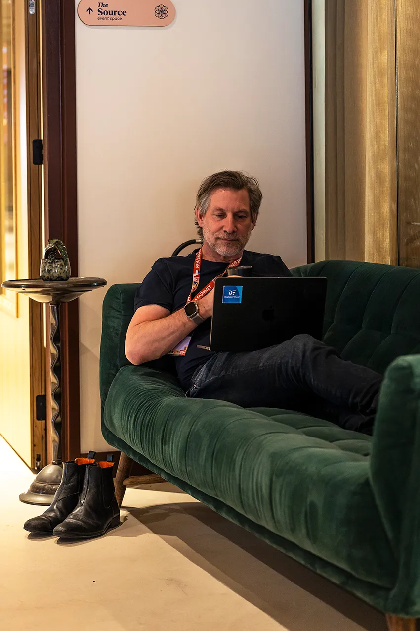 Martijn Aslander op de PKM Summit, schoenen uit, laptop open, aan het bouwen.